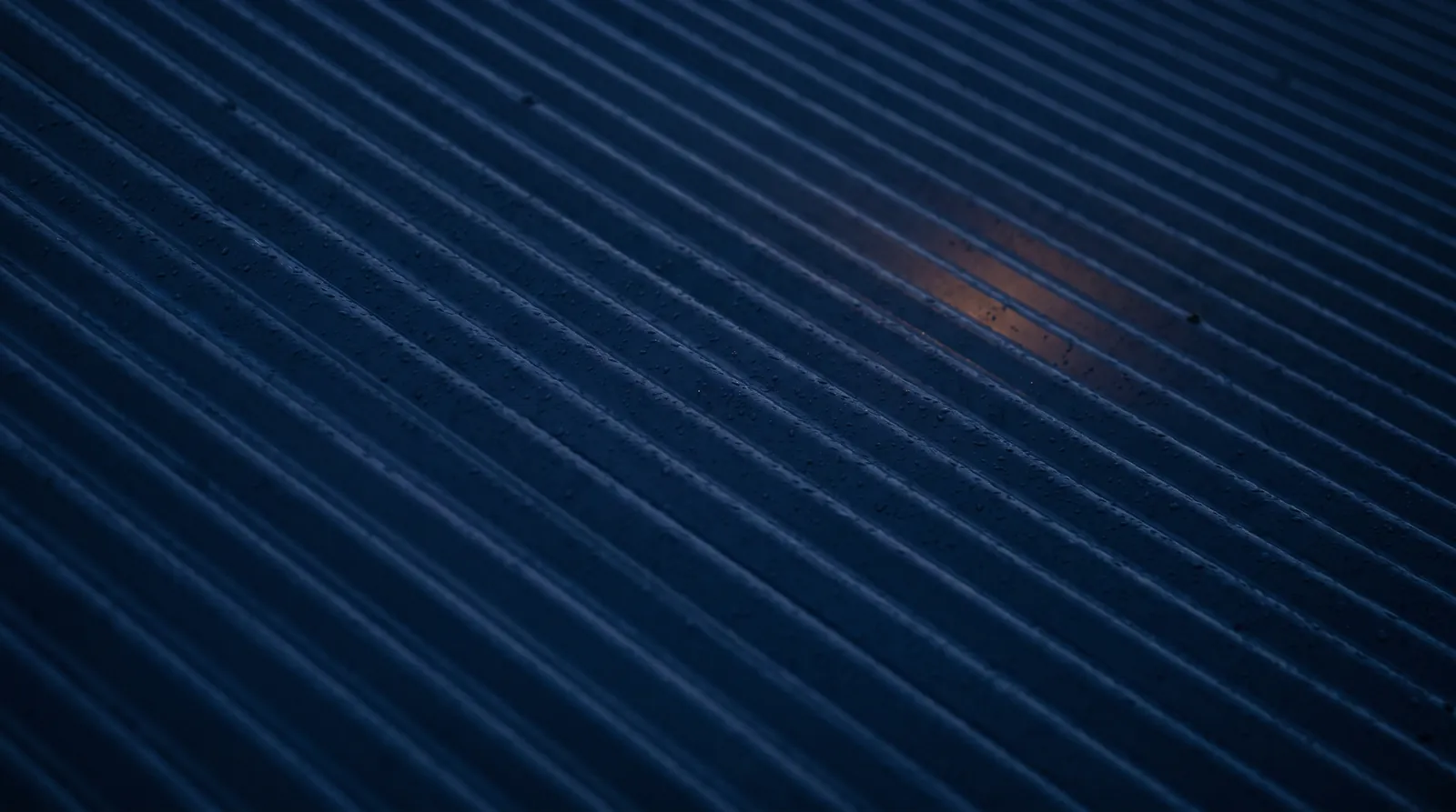 Wet Colorbond roof ridges at night