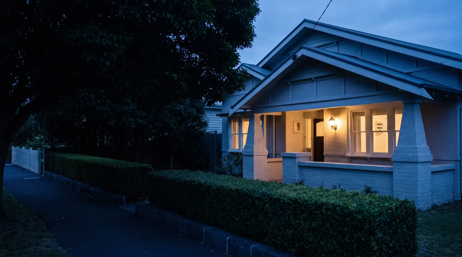A Californian bungalow at blue hour with the porch light on