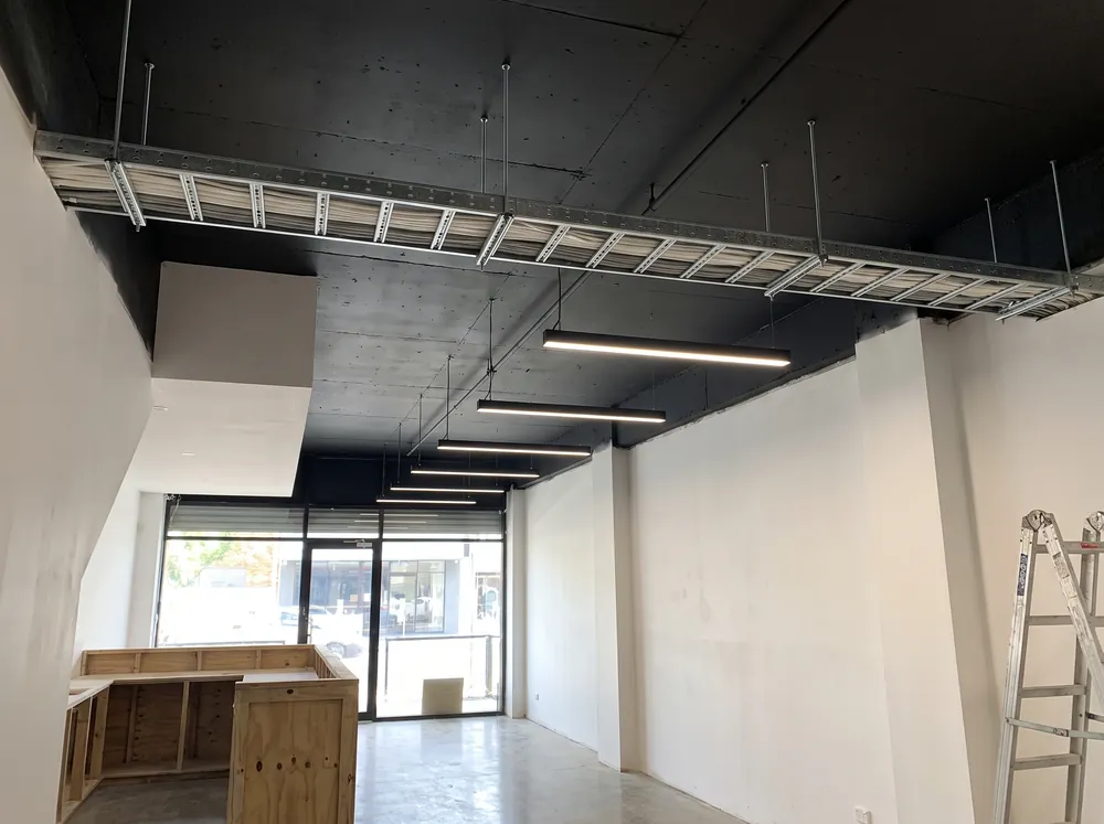 A shop fit-out ceiling with cable tray and linear lighting