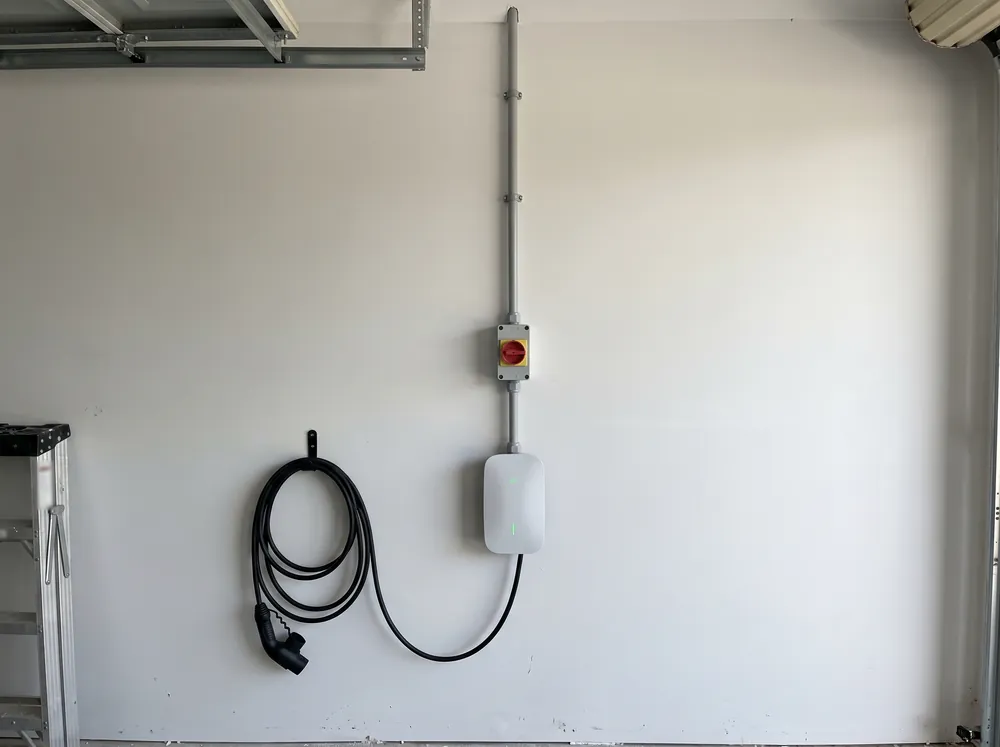 A hand docking an EV charging plug in its wall holster
